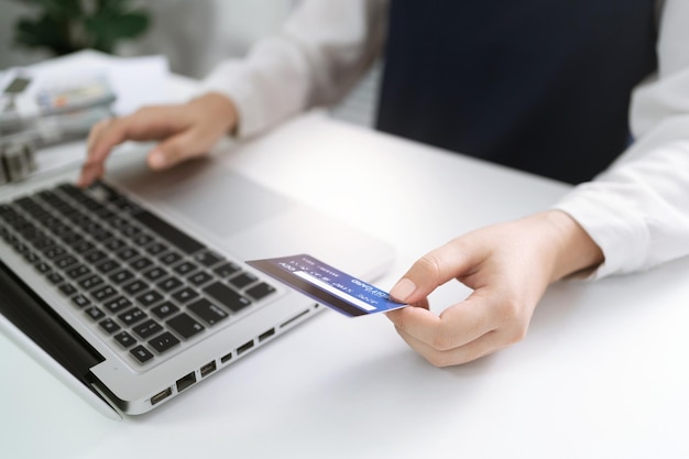 Mujer con tarjeta de crédito y usando una computadora portátil para compras de comercio electrónico en línea de Internet gastando dinero Concepto de tecnología de computadora portátil de compras en línea Pago de compras en línea con concepto de tarjeta de crédito