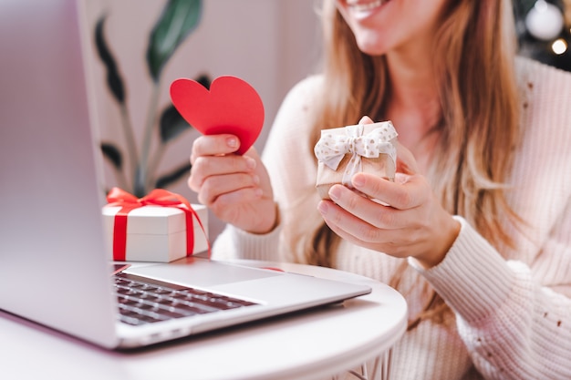 Mujer con tarjeta de San Valentín y regalo con un video chat en portátil