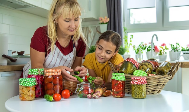 Mujer con tarro de verduras en conserva para el invierno madre e hija Enfoque selectivo