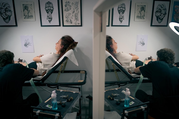 Mujer se tatua la pierna en un acogedor estudio decorado con obras de arte