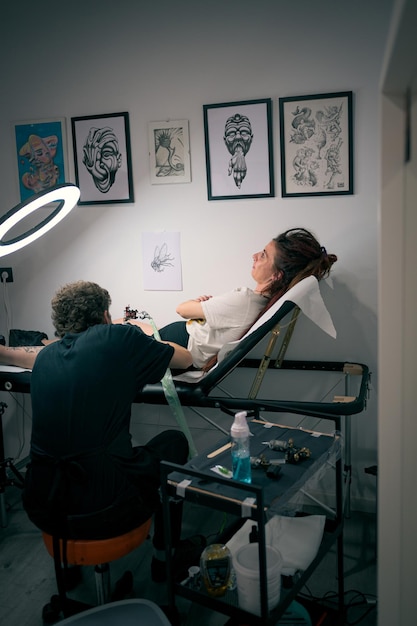 Mujer se tatua la pierna en un acogedor estudio decorado con obras de arte
