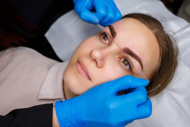 Mujer con tatuaje de maquillaje permanente en las cejas. Esteticista de primer plano hace un boceto de las cejas. Maquillaje profesional y cuidado cosmético de la piel.