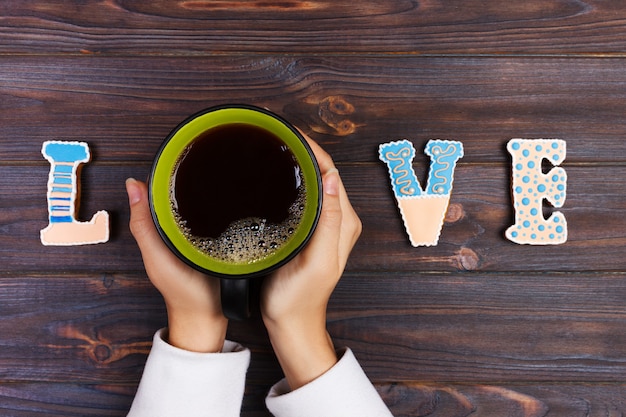 Foto mujer con una taza de café caliente, con galletas. concepto de amor amor palabra con cafe