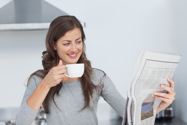 Mujer con una taza de café leyendo un periódico