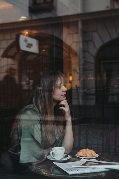 Mujer con taza de café en la mesa