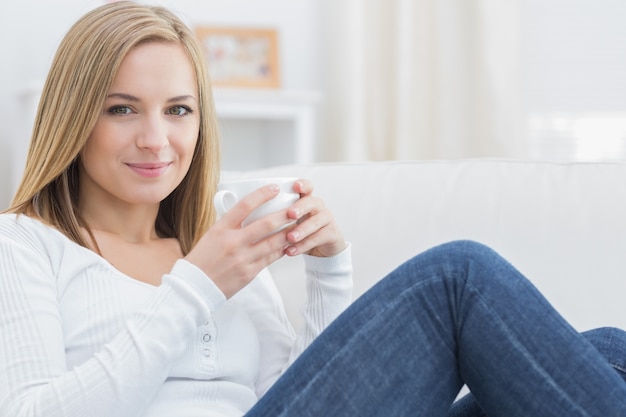 Mujer con taza de café sentado en el sofá