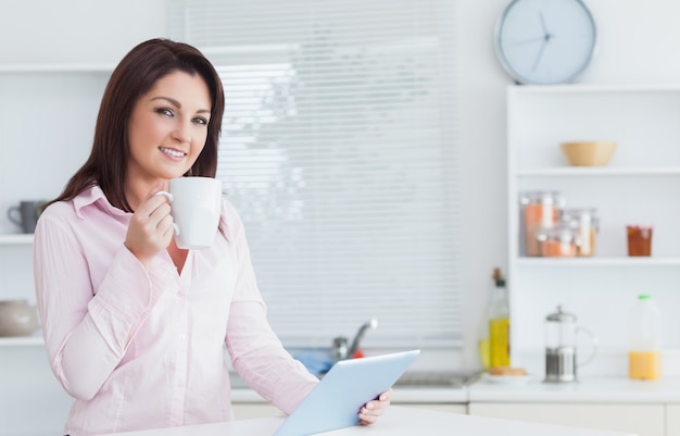 Mujer con taza de café y tableta digital