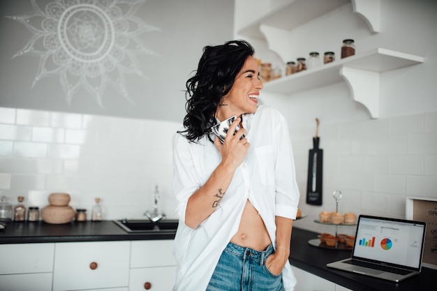 Foto mujer con taza de pie en la cocina