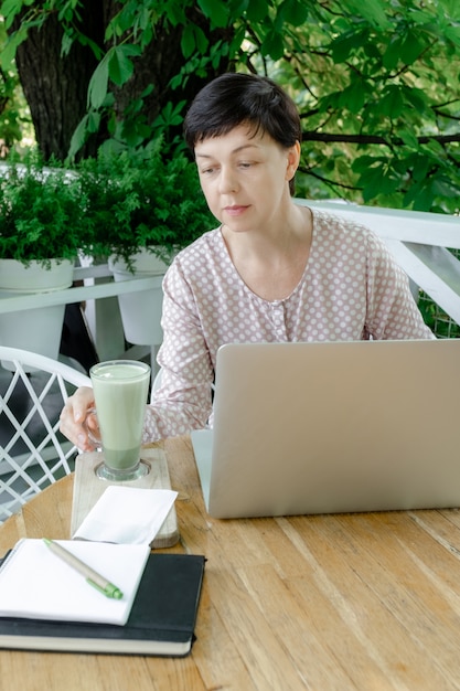 Mujer taza verde matcha latte café té lugar de trabajo cafe terassa 50 plus freelance
