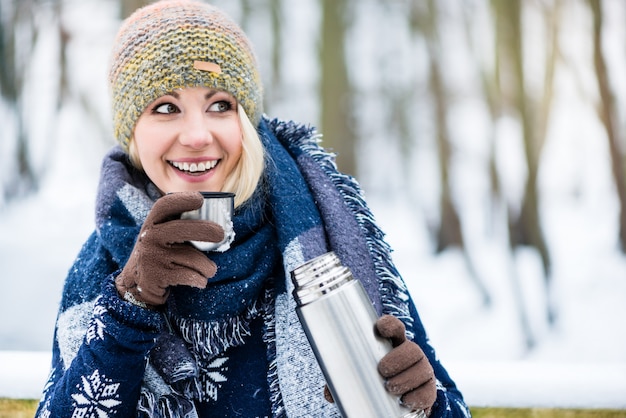 Mujer con té o café caliente en una caminata de invierno