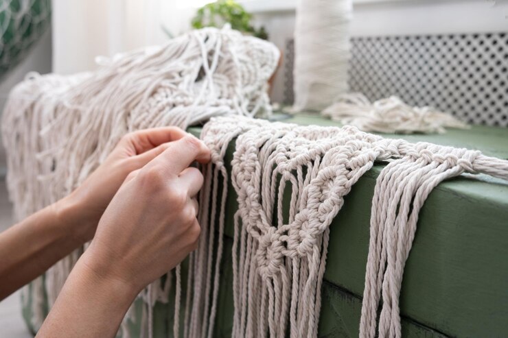 Foto la mujer teje en casa decoración hecha a mano a partir de hilo de algodón macrame proceso de creación de paneles macrame