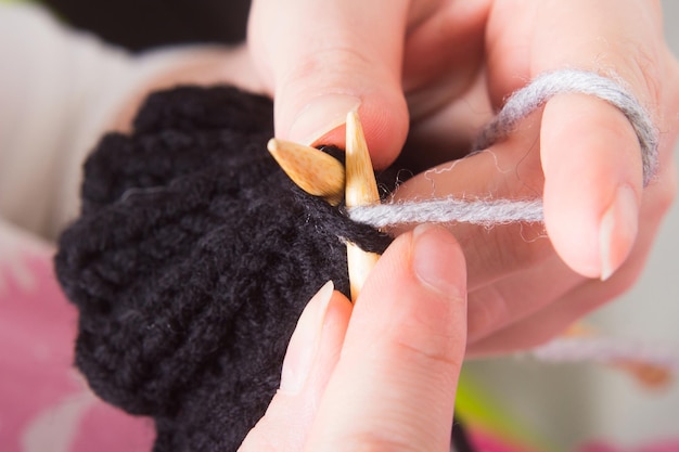 La mujer teje en el primer plano de las agujas. La producción de ropa hecha a mano.