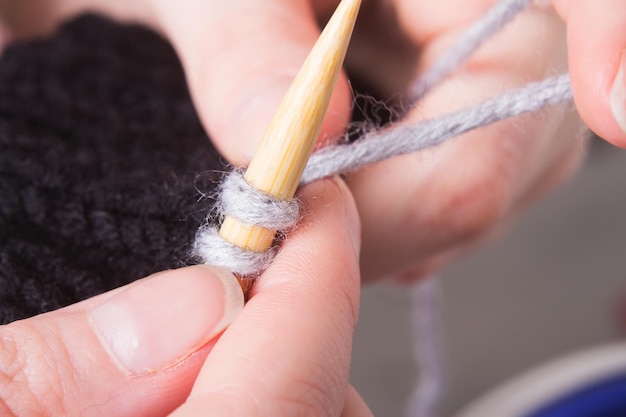 La mujer teje en el primer plano de las agujas. La producción de ropa hecha a mano.