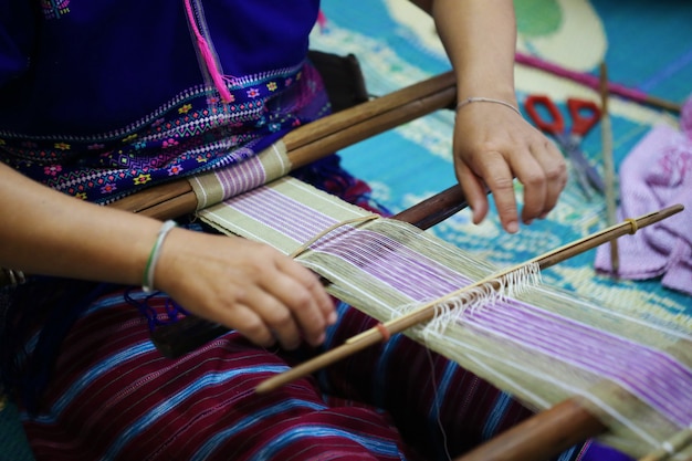 Mujer tejiendo patrón azul y blanco en telar, cultura de tribu de colina, chiang mai