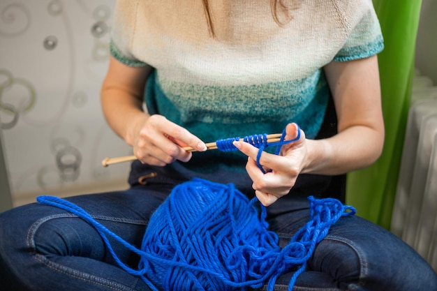 Mujer tejiendo un suéter de hilo azul