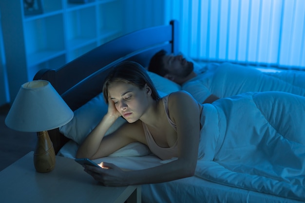 La mujer telefonea en el dormitorio. Noche