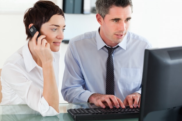 Foto mujer telefoneando mientras su colega está usando una computadora