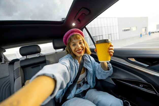 Foto mujer con teléfono y café en el asiento trasero de un coche