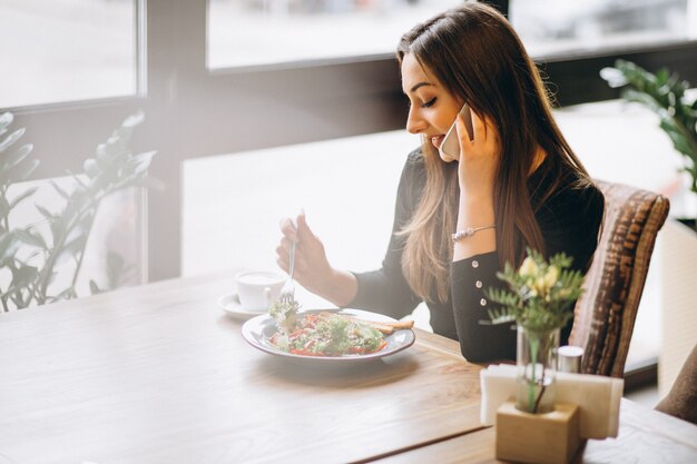 Mujer con teléfono café y ensalada