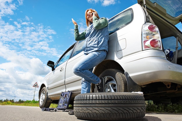 Mujer con teléfono está llamando al servicio del coche.