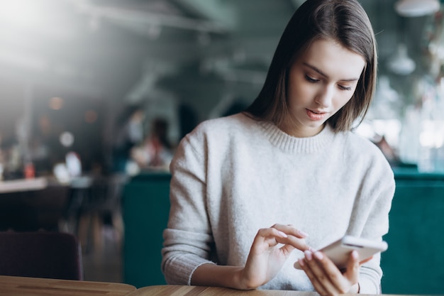 mujer con teléfono inteligente en café