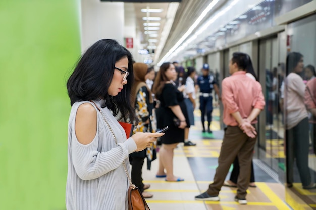 Mujer con teléfono inteligente esperando el MRT de Yakarta