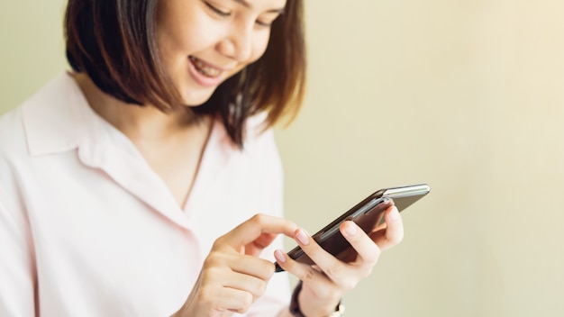 Mujer con teléfono inteligente en la habitación, durante el tiempo libre. El concepto de usar el teléfono es esencial.