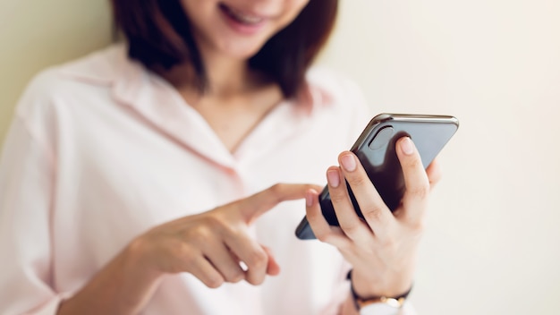 Mujer con teléfono inteligente en la habitación, durante el tiempo libre.