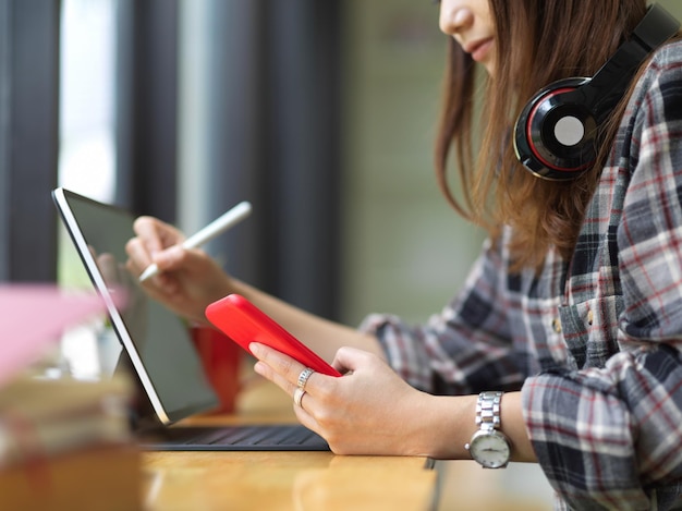 Mujer con teléfono inteligente mientras está sentada en la mesa