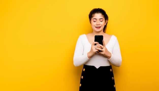 Mujer y teléfono inteligente Mujer de negocios sonriente que usa un teléfono inteligente con una sonrisa brillante alegre y feliz en un espacio de copia de fondo amarillo