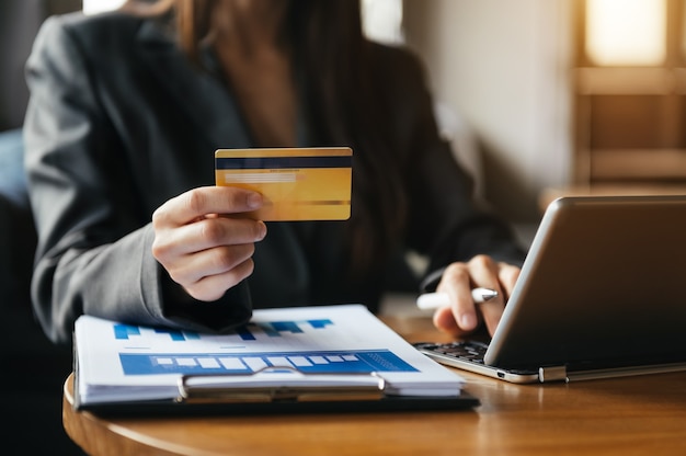 Mujer con teléfono inteligente para pagos móviles, compras en línea, omni canal, sentado en la mesa, pantalla de interfaz gráfica de iconos virtuales a la luz de la mañana