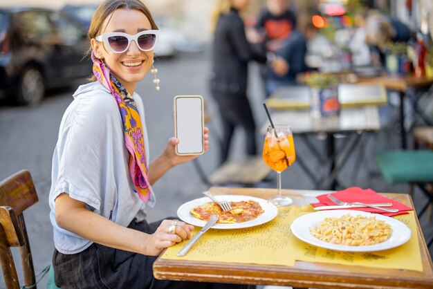 Mujer con teléfono inteligente en el restaurante al aire libre