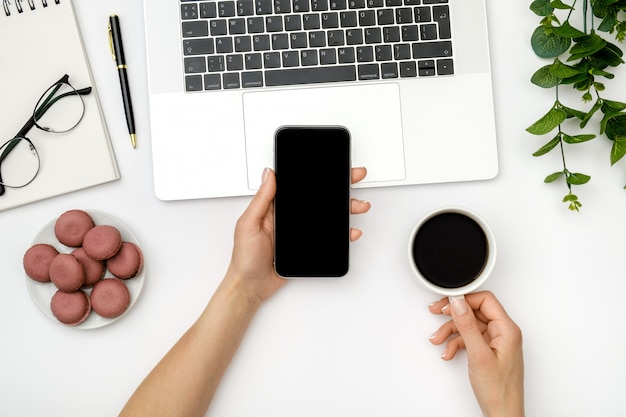 Mujer con teléfono inteligente y tomando café en la oficina