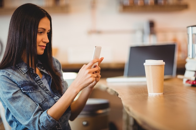 Mujer con teléfono móvil en la cafetería de la oficina