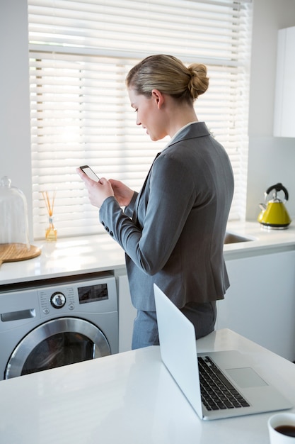 Mujer con teléfono móvil en la cocina