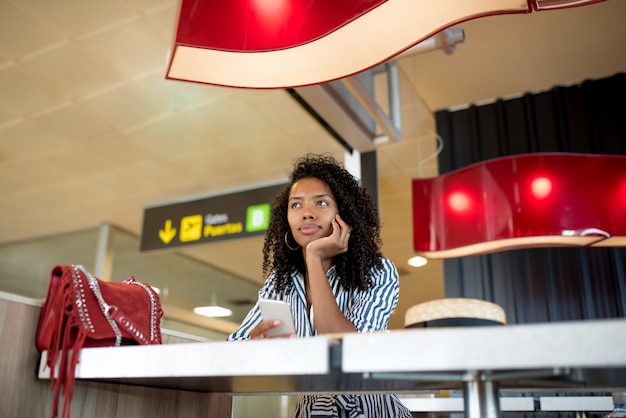 Foto mujer en el teléfono móvil esperando su vuelo en el aeropuerto