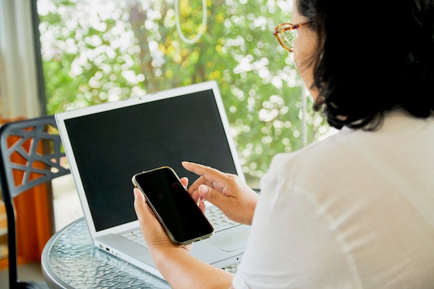 Mujer con teléfono móvil inteligente y portátil