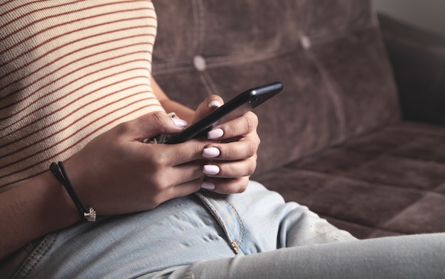 Mujer con teléfono móvil mientras está sentado en un sofá en casa