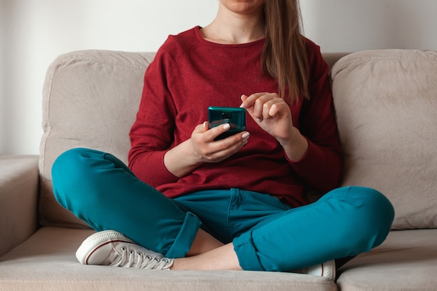 Mujer con teléfono móvil, sosteniendo en las manos sentado en el sofá