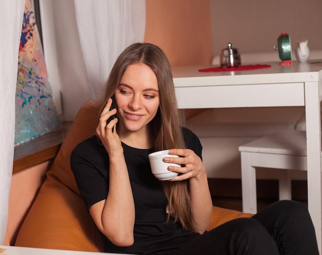 Mujer con teléfono móvil y taza de café.