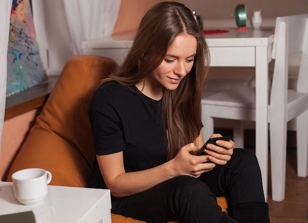 Mujer con teléfono móvil y taza de café.