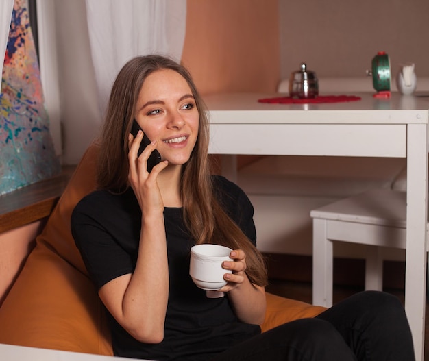 Mujer con teléfono móvil y taza de café.