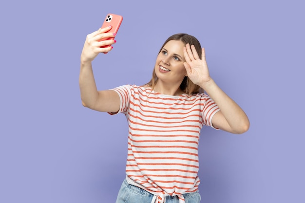 Mujer con teléfono móvil y videollamada con hola o adiós con la mano