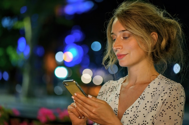 Mujer con teléfono noche retrato ciudad luces bokeh.