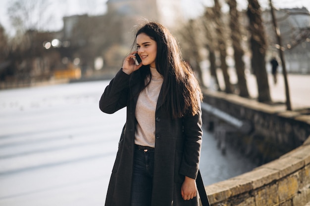 Mujer con teléfono en el parque junto al lago en invierno