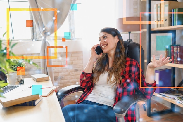 Mujer teletrabajadora trabaja en casa con una computadora portátil y un teléfono inteligente