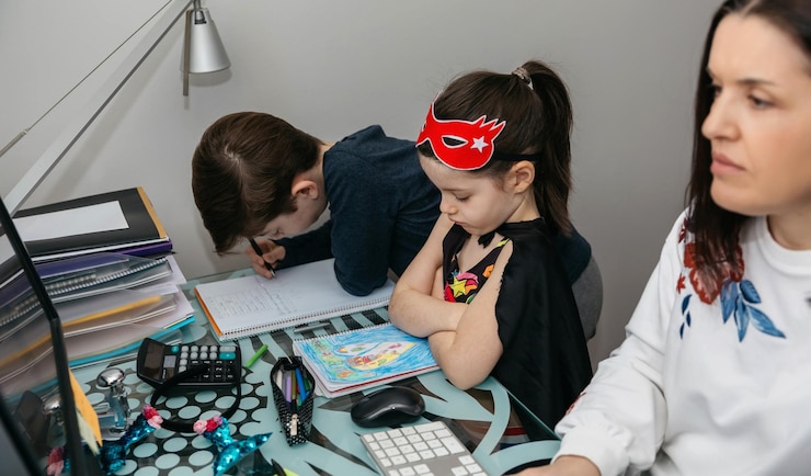 Foto mujer teletrabajando con su hijo y su hija enojada