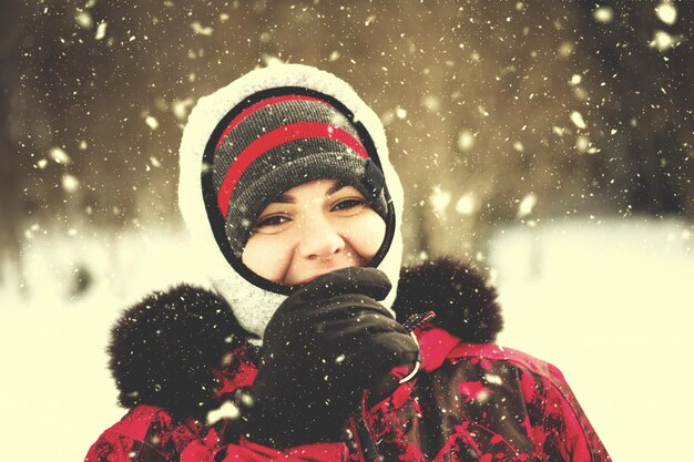 Mujer en temporada de invierno Retrato de mujer joven en ropa de abrigo disfrutando de un día de nieve con copos de nieve a su alrededor en el bosque de invierno