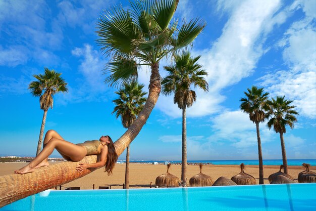 mujer tendida en la piscina tronco de palmera doblada