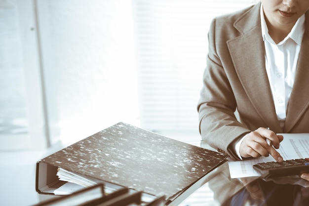 Mujer tenedora de libros o inspectora financiera haciendo informes, calculando o comprobando el saldo, primer plano. Conceptos de negocio, auditoría o impuestos.